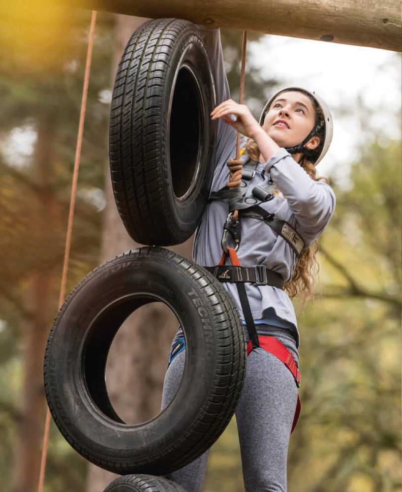 A woman climbing some tires.