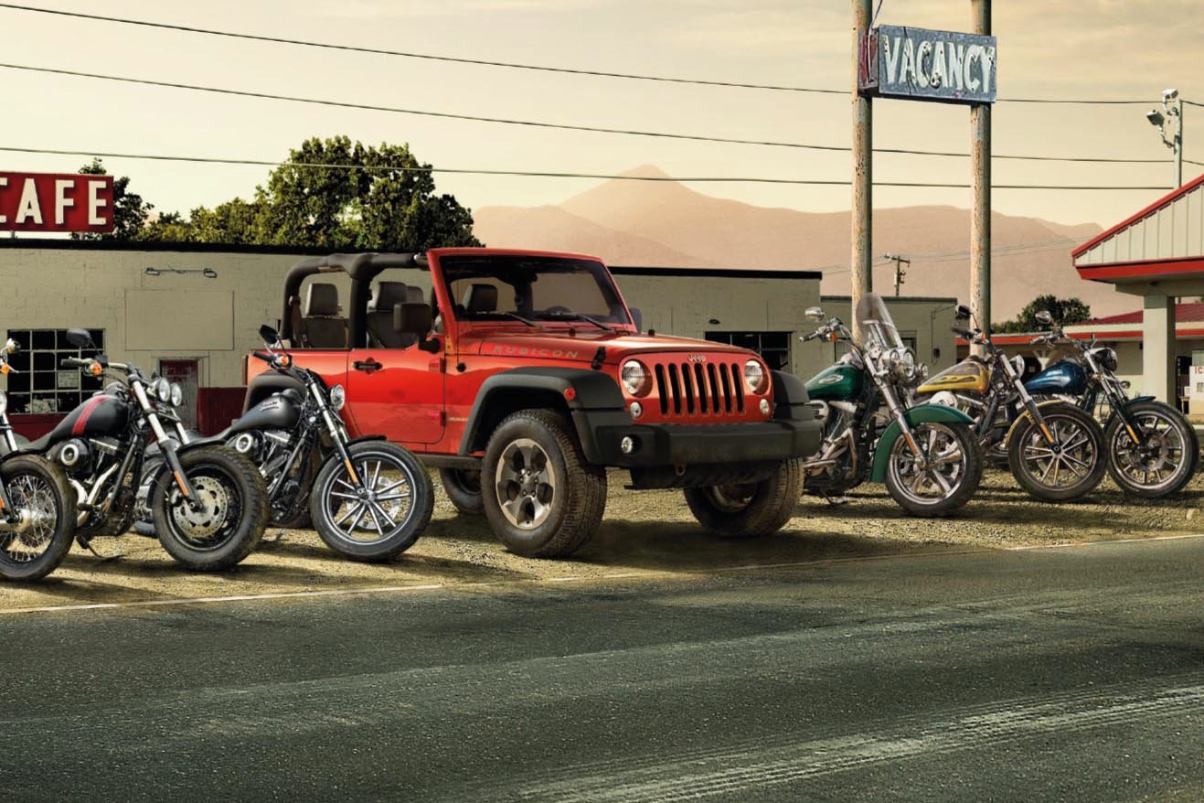 A jeep parked between Harley Davidson motorbikes