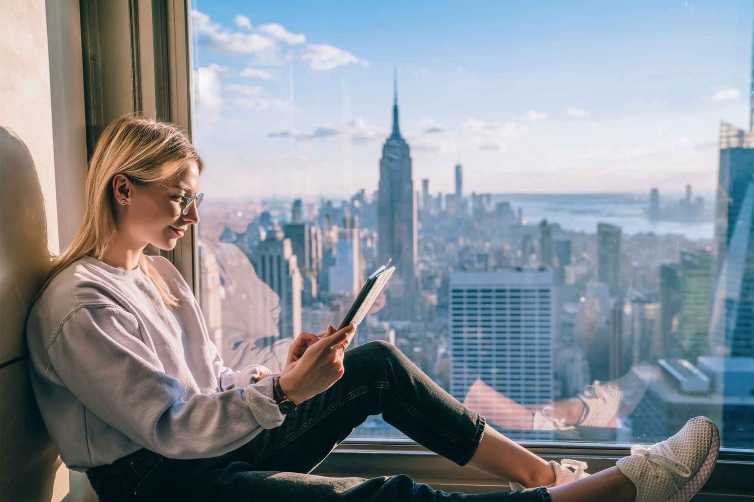 Woman reading content on her iPad whilst sitting in a hotel window