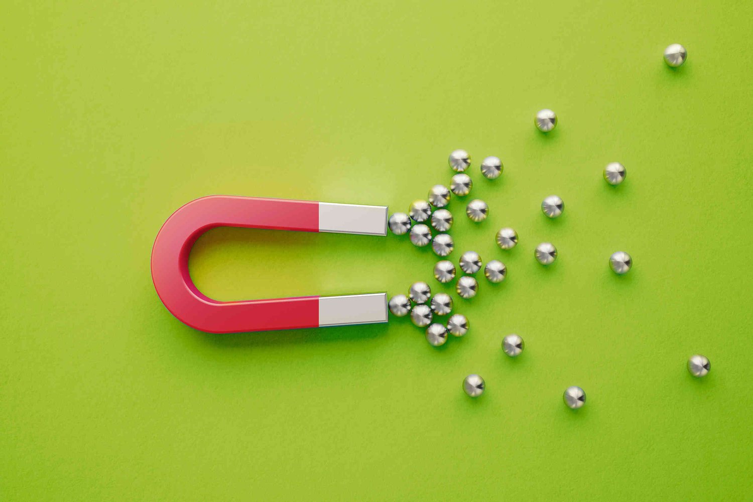 Horseshoe magnet on a green background attracting ball bearings 
