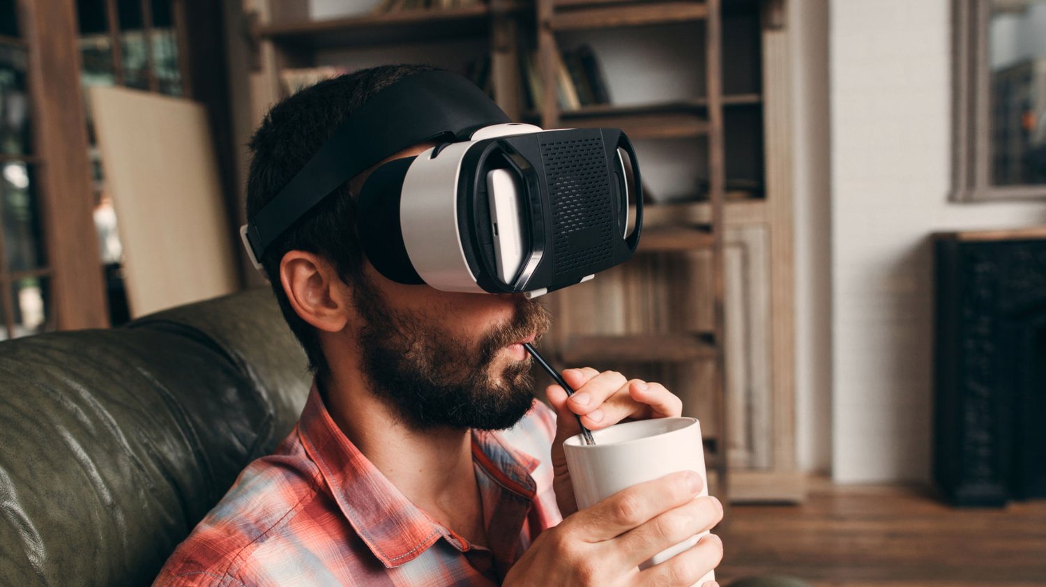 Man wearing VR headset and sipping on drink through straw