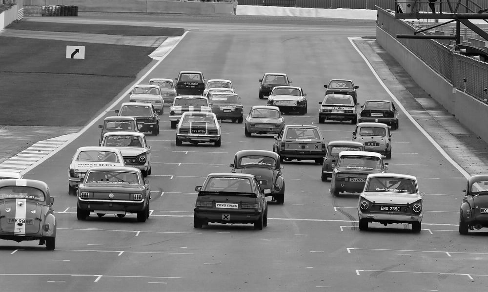 A tight pack of classic cars on the racetrack