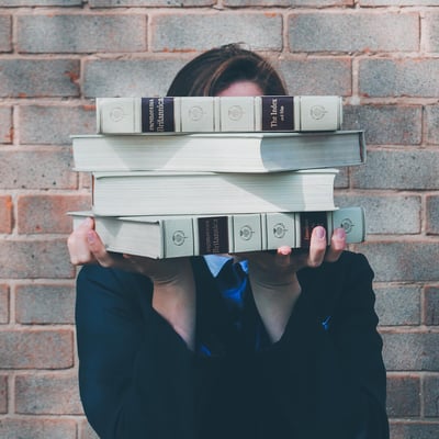 School girl holding large encyclopedias