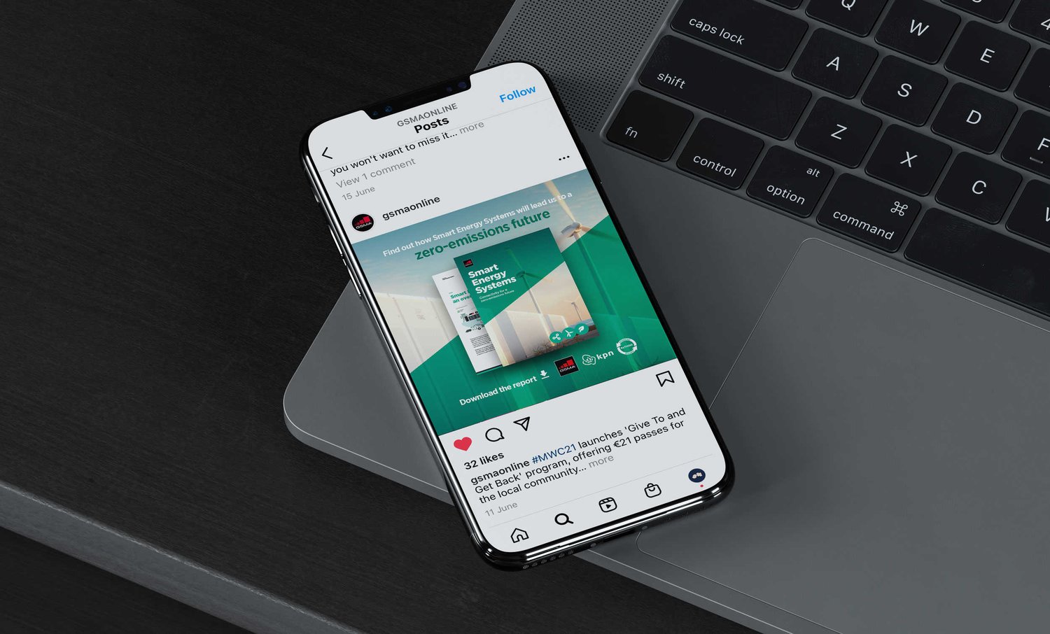 A smartphone on the edge of a laptop displaying the GSMA instagram account