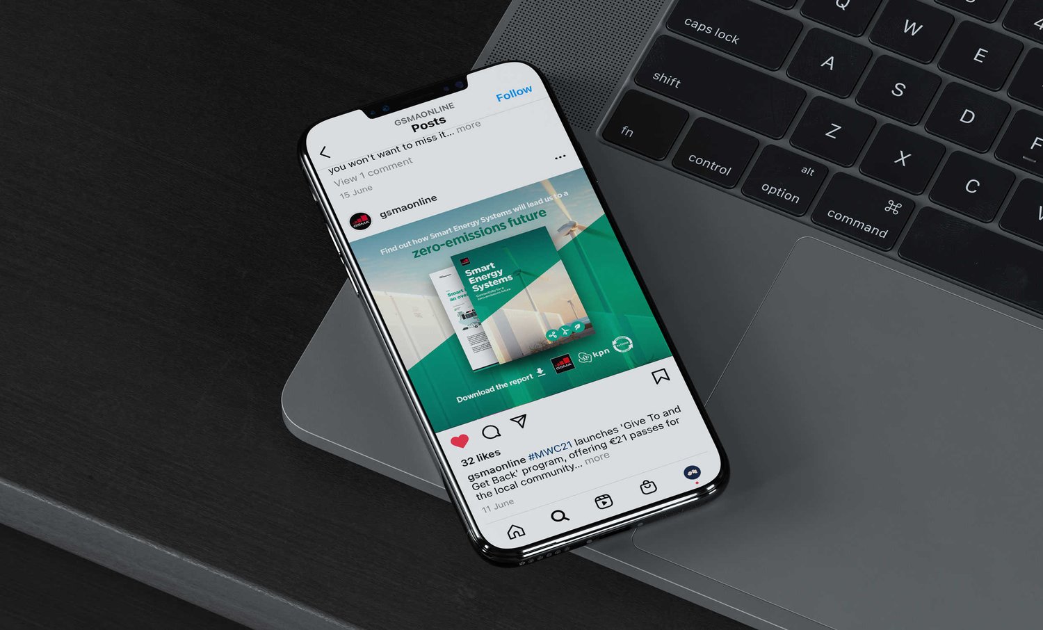 A smartphone on the edge of a laptop displaying the GSMA instagram account