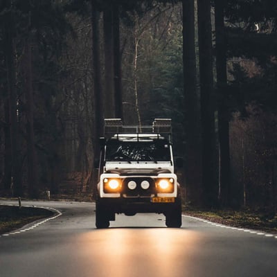 A white Jeep drives down a forest road