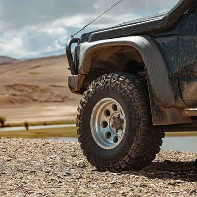 A close up of a dirt streaked Jeep wheel