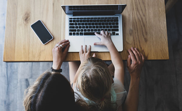 parent and child working on macbook at desk