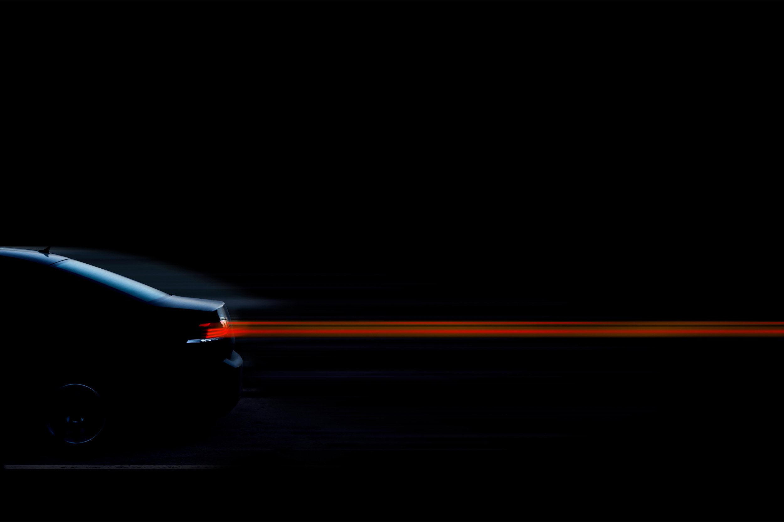 Rear of a dark blue car at night, with red taillight streaks extending across a black background